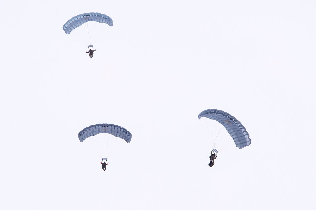 Alaska Air National Guard personnel descend over Malemute drop zone during precision parachute training.