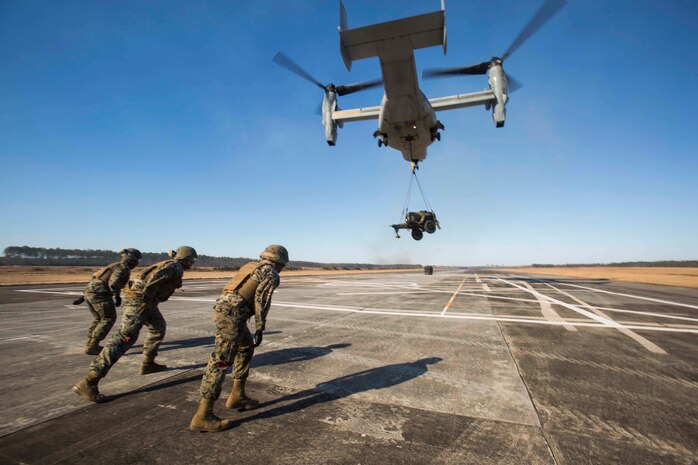 Marines with Landing Support Company, 2nd Transportation Support Battalion, 2nd Marine Logistics Group brace themselves for the high winds produced by a MV-22 osprey as it lifts a 400 gallon M-149 water tank trailer during sling load operations at Camp Lejeune, N.C., Jan. 25, 2018. during sling load operations at Camp Lejeune, N.C., Jan. 25, 2018. The Marines conducted sling load operations to improve their proficiency with loading equipment onto aircraft for transportation. (U.S. Marine Corps photo by Sgt. Chris Garcia)