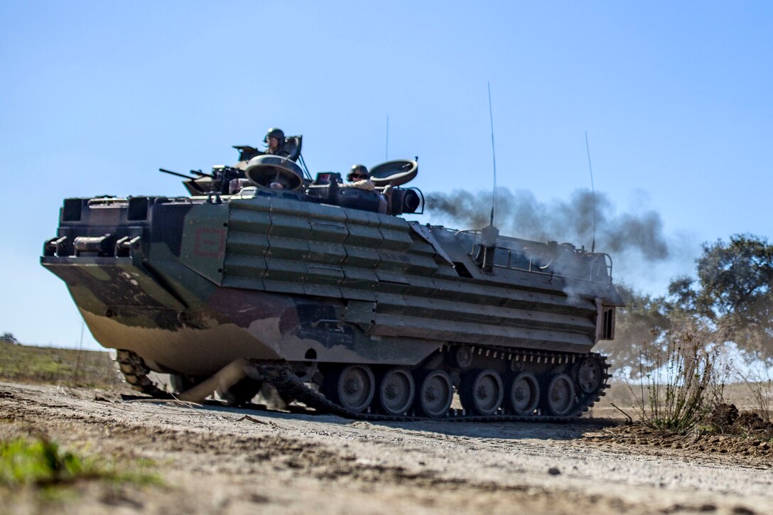 Marines ride in a vehicle on a dirt road.