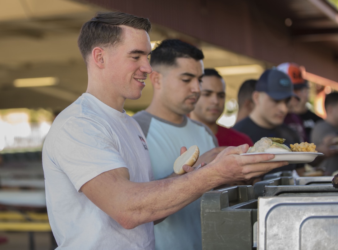 U.S. Marine Corps Air Traffic Controller Cpl. Steven Goller, assigned to Headquarters & Headquarters Squadron (H&HS) at Marine Corps Air Station Yuma, Ariz., receives food during the H&HS Barracks Bash at Ramada Field Jan. 18, 2018. H&HS leadership and the station Single Marine Program coordinated the event to boost morale through fun, friendly competition.  (U.S. Marine Corps photo taken by Lance Cpl. Sabrina Candiaflores)