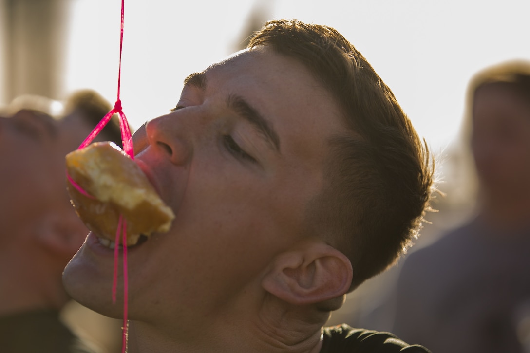 U.S. Marine Corps Flight Line Mechanic Lance Cpl. Shay Valdivieso, assigned to the Search and Rescue Unit with Headquarters & Headquarters Squadron (H&HS) at Marine Corps Air Station Yuma, Ariz., participates in the Donut Challenge, where Marines had to eat a pastry without using their hands during the H&HS Barracks Bash at Ramada Field Jan. 18, 2018. H&HS leadership and the station Single Marine Program coordinated the event to boost morale through fun, friendly competition. (Lance Cpl. Sabrina Candiaflores)
