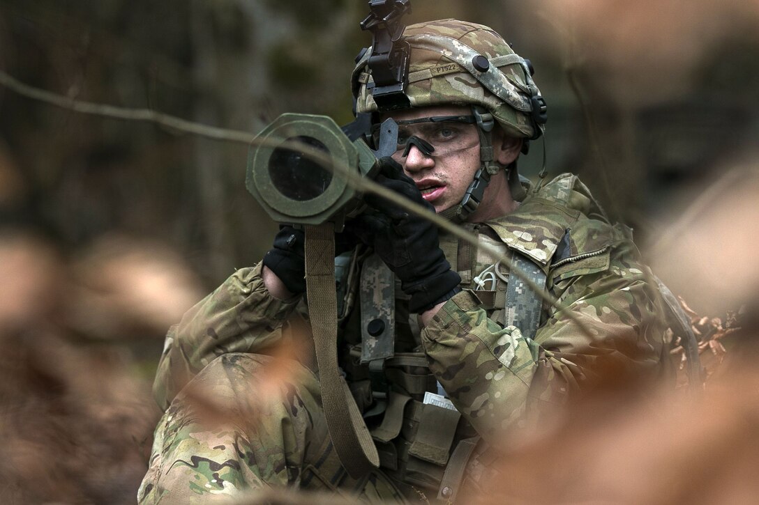 A soldier aims an antiarmor weapon while in the brush.