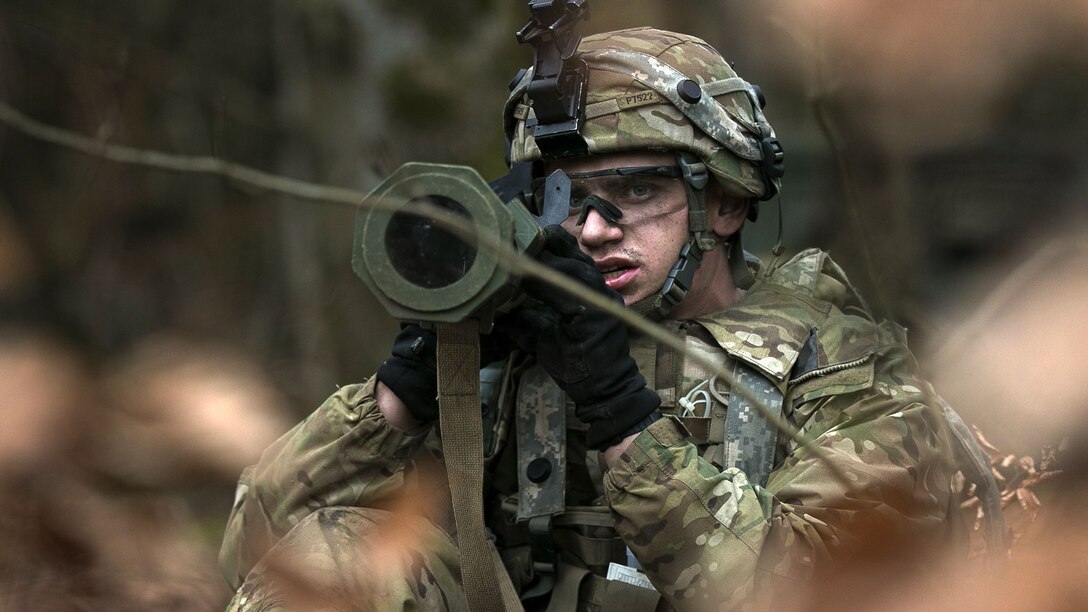 A soldier aims an antiarmor weapon while in the brush.