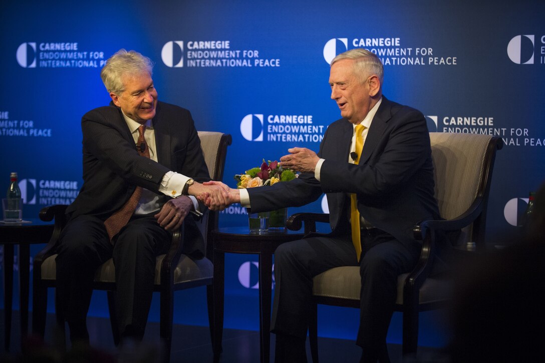 Defense Secretary James N. Mattis shaking hands with an ambassador while seated on stage.