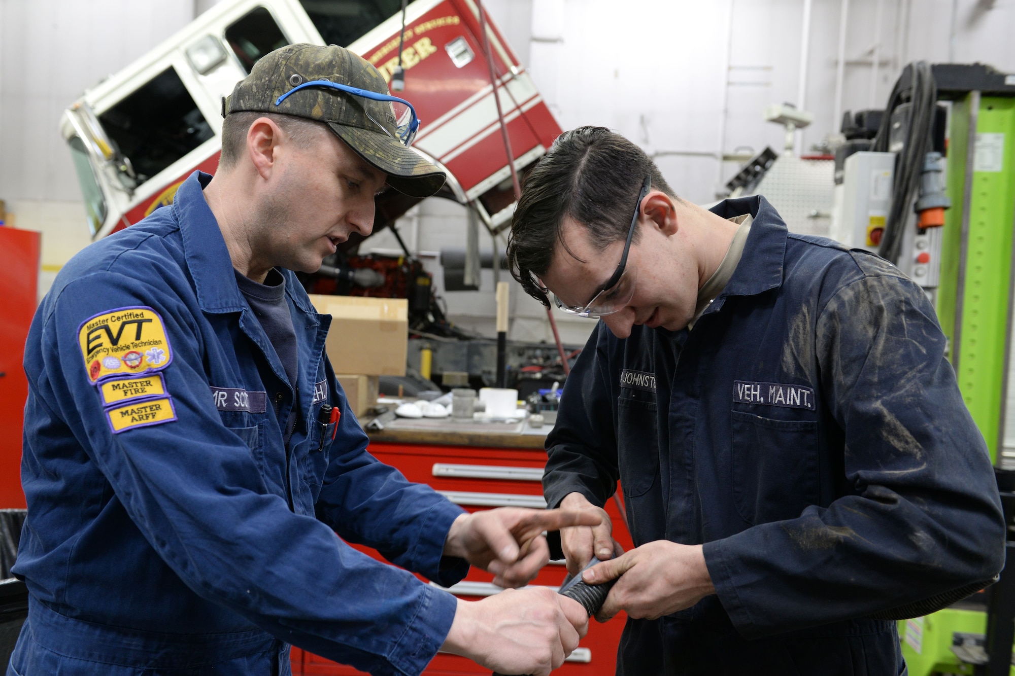 Oral Scott, lead fire truck mechanic, teaches Airman 1st Class Nicholas Johnston, Fire truck maintenance apprentice with the 673d Logistics Readiness Squadron Vehicle Maintenance, Fire Truck Maintenance shop, how to put wire loom over coolant hose Jan. 25, 2018, at Joint Base Elmendorf-Richardson, Alaska. The Fire Truck Maintenance shop repairs and services all fire trucks at JBER.