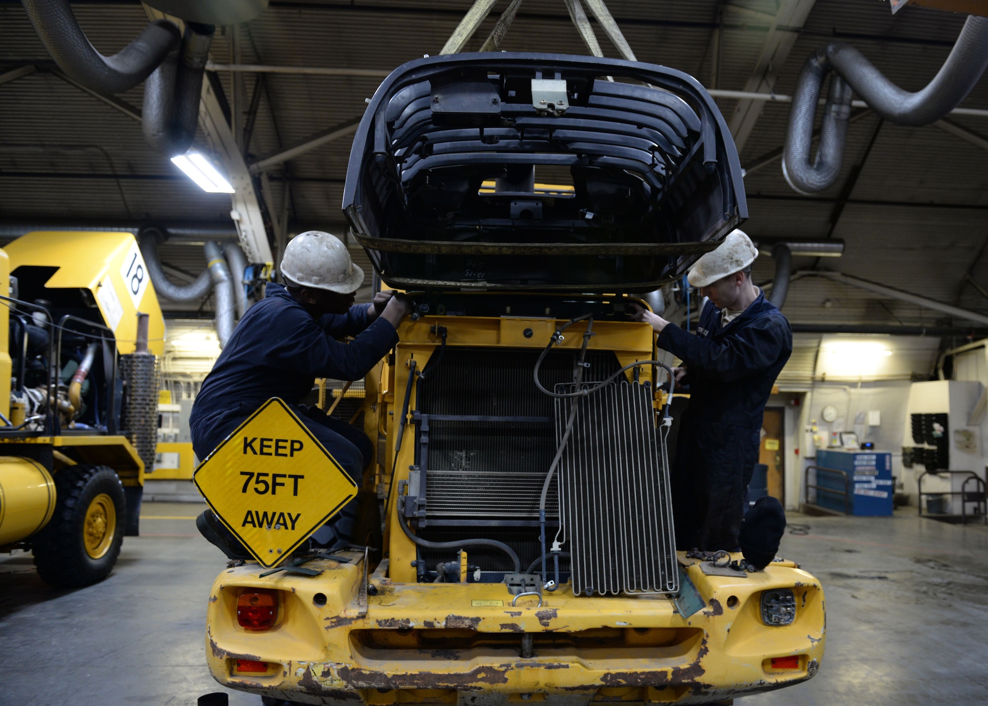 Airman 1st Class Henry Wilson and Senior Airman Samuel Reilly, a mission general vehicle equipment maintenance airmen, with the 673d Logistics Readiness Squadron Vehicle Maintenance, Heavy Equipment shop, inserts the bolts attaching a cover panel on to a L60F loader, Jan. 25, 2018, at Joint Base Elmendorf-Richardson, Alaska. The Heavy Equipment shop repairs and services all snow-removal and road equipment at JBER.