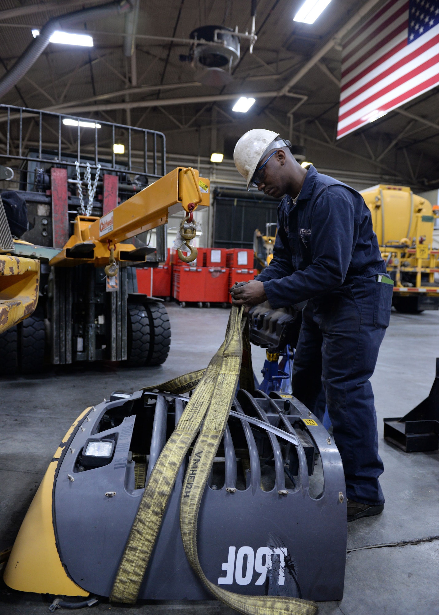 Airman 1st Class Henry Wilson, a mission general vehicle equipment maintenance apprentice with the 673d Logistics Readiness Squadron Vehicle Maintenance, Heavy Equipment shop, places tie-straps around a cover, Jan. 25, 2018, at Joint Base Elmendorf-Richardson, Alaska. The Heavy Equipment shop repairs and services all snow-removal and road equipment at JBER.