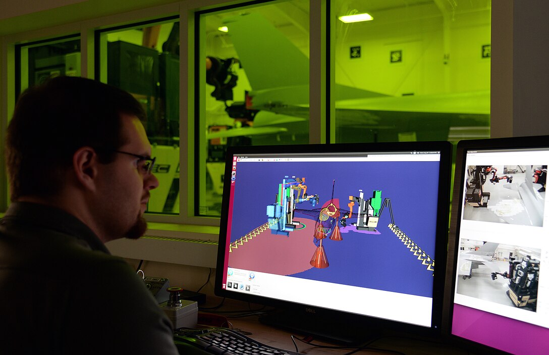 Cory Yambor, contrator supporting the Ogden Air Logistics Complex Engineer Directorate, watches over the controls of the robotic laser depainting equipment on Aug. 29, 2016, at Hill Air Force Base, Utah. The system reduces the time it takes to strip old paint off F-16s and completes the task without use of harmful chemicals. (U.S. Air Force photo by Alex R. Lloyd)