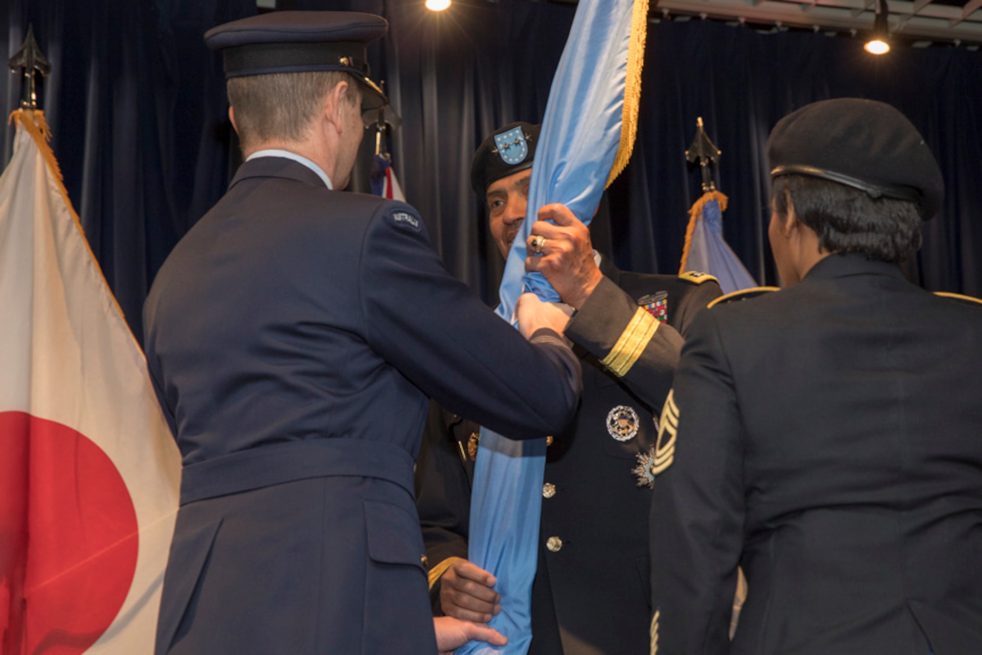 Royal Australian Air Force Group Captain Michael W. Jansen, outgoing United Nations Command (Rear) commander, passes the guidon to U.S. Army General Vincent K. Brooks, United Nations Command, Combined Forces Command and U.S. Forces Korea commanding general during a change of command ceremony
