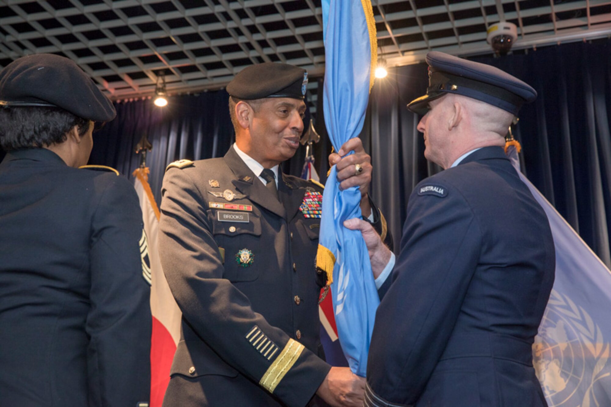 Royal Australian Air Force Group Captain Adam Williams, incoming United Nations Command (Rear) commander, receives the guidon from U.S. Army General Vincent K. Brooks, United Nations Command, Combined Forces Command and U.S. Forces Korea commanding general during a change of command ceremony