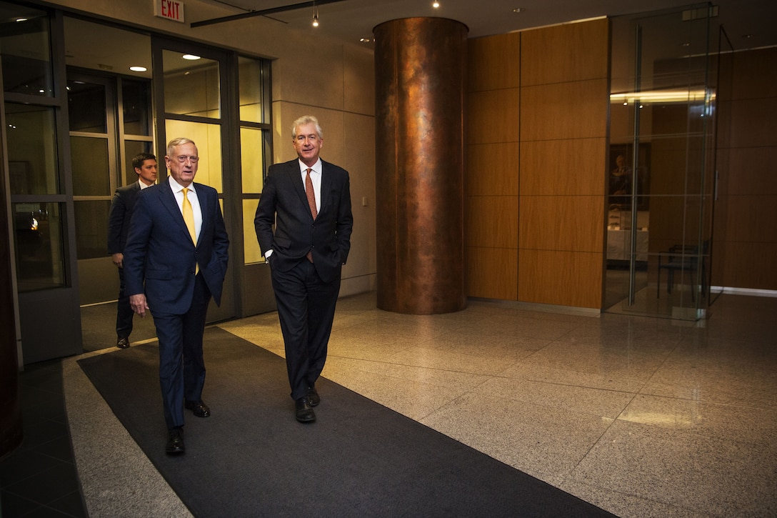 Defense Secretary James N. Mattis walking with the ambassador in a large hallway.