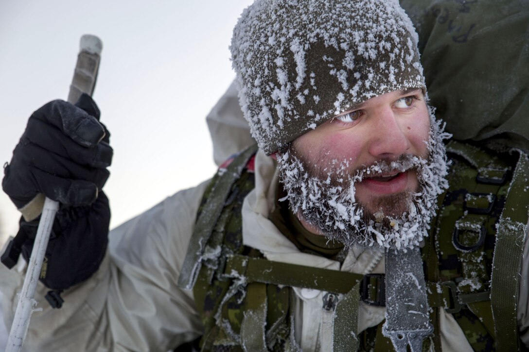 A Marine's winter cap and beard are covered in snow and ice.