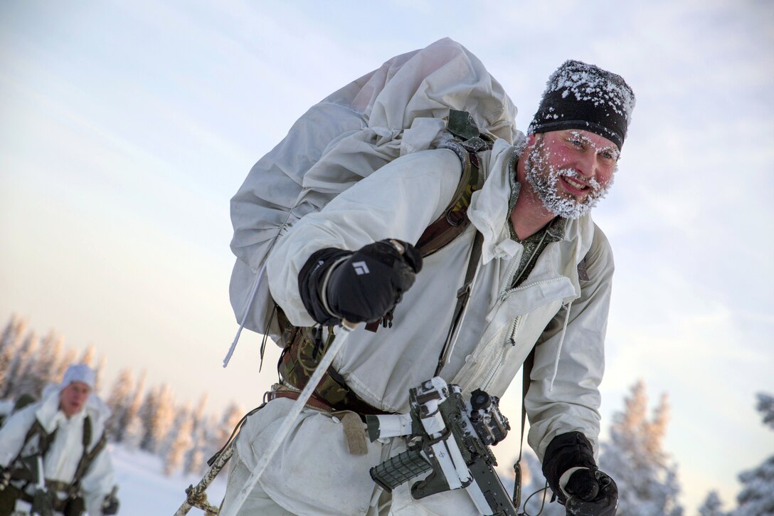 A Marine skiing with snow and ice covering his winter cap and beard.