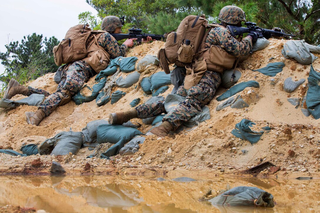 Marine Corps Lance Cpls. Zimmerman Thomas, left, and Menkara-Hetep Gamle provide security from behind a berm.