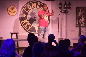 A sailor does stand-up comedy on a stage in Florida.