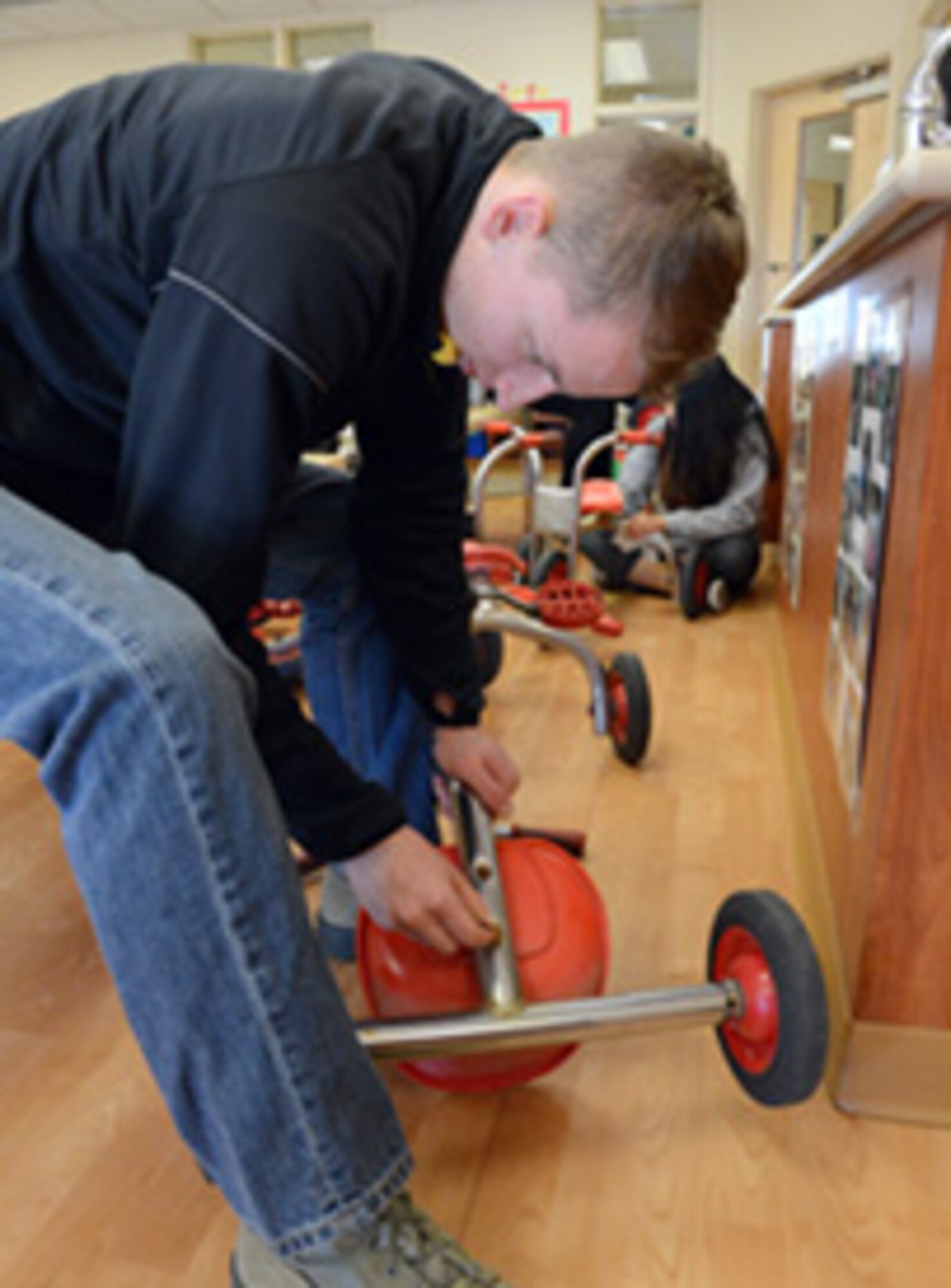 Airman 1st Class Luke Rhoney, 552nd Maintenance Squadron, sands tricycles at the Child Development Center East.