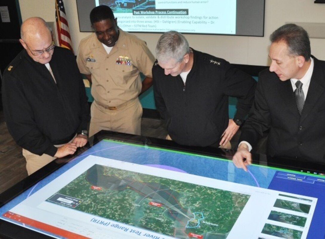 IMAGE: DAHLGREN, Va. (Jan. 16, 2018) – Naval Surface Warfare Center Dahlgren Division (NSWCDD) Innovation Lab (iLab) Director of Innovation Nelson Mills briefs the Commander of Naval Sea Systems Command (NAVSEA) Vice Adm. Thomas Moore, NAVSEA Command Master Chief Robert Crossno, and NSWCDD Commanding Officer Capt. Gus Weekes, on the use of digital collaboration tables as visual aids for surface ships. The collaboration table could provide capabilities to view ship doctrine, navigation tracks, radar information, and Automatic Identification System information for situational awareness. The iLab – equipped with state-of-the-art equipment, services, and trained personnel – opened for business last summer as an intensive collaborative environment where the command's experts work to speed up and maximize corporate innovative solutions across the laboratory. 

The iLab was one stop in the admiral's tour of Dahlgren, which gave him an opportunity to meet with the command's leaders, scientists, and engineers. It was the first in a series of scheduled visits to the NAVSEA Warfare Center divisions under the theme of “Warfare Centers – The Campaign Plan in Action.” While at the iLab, Weekes briefed the NAVSEA commander on Dahlgren technical programs, including directed energy, electromagnetic railgun, chemical, biological, and radiological defense, as well as leadership development. Moore's Campaign Plan is focused on three mission priorities: on-time delivery of ships and submarines, culture of affordability, and cybersecurity. These priorities address today's challenges and provide the focus to achieve NAVSEA's mission and support the Fleet.