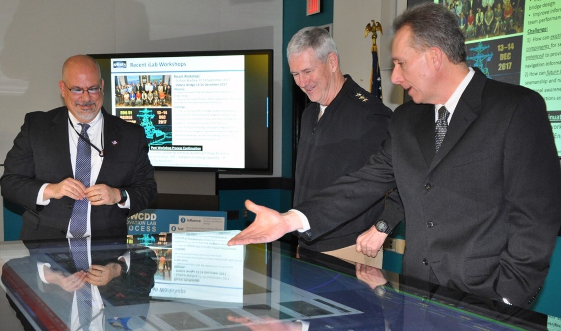 IMAGE: DAHLGREN, Va. (Jan. 16, 2018)  – Naval Surface Warfare Center Dahlgren Division (NSWCDD) Innovation Lab (iLab) Director of Innovation Nelson Mills briefs the Commander of Naval Sea Systems Command (NAVSEA) Vice Adm. Thomas Moore and NSWCDD Technical Director John Fiore on the use of digital collaboration tables as visual aids for surface ships. The collaboration table could provide capabilities to view ship doctrine, navigation tracks, radar information, and Automatic Identification System information for situational awareness. The iLab – equipped with state-of-the-art equipment, services, and trained personnel – opened for business last summer as an intensive collaborative environment where the command's experts work to speed up and maximize corporate innovative solutions across the laboratory.