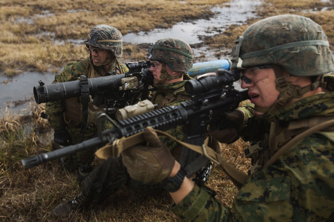 Marines aim guns at simulated targets.