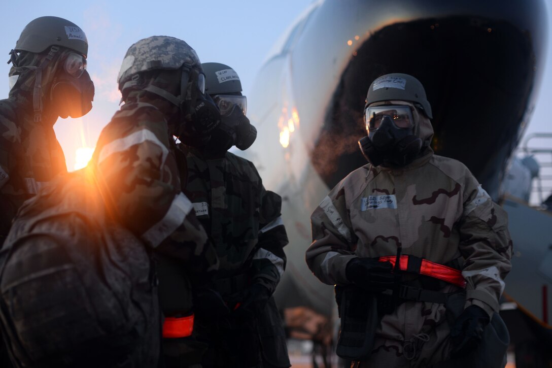 Four airmen in full gear stand on a flightline.