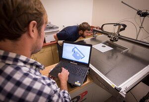 SPAWAR Systems Center (SSC) Atlantic employee Josh Heller, left, reviews CAD software designs for additive manufacturing while Ryan Wilhite verifies the printer is properly calibrated. By using Additive Manufacturing technology (aka 3D printing), SSC Atlantic engineers and scientists can design and create prototypes for new components and replacement parts, and enhance and modify existing products. SSC Atlantic develops, acquires and provides life cycle support for command, control, communications, computer, intelligence, surveillance and reconnaissance (C4ISR) systems, information technology and space capabilities. A leading-edge Navy engineering center, SSC Atlantic designs, builds, tests, fields and supports many of the finest frontline C4ISR systems in use today, and those being planned for the future.