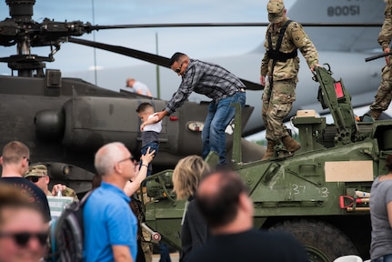 A father helps his son down after U.S. Army Soldiers assigned to the 1st Platoon, 95th Chemical Company, U.S. Army Alaska, provide a demonstration of a Stryker vehicle during the Arctic Thunder Open House at Joint Base Elmendorf-Richardson, Alaska, July 1, 2018. During the biennial open house, JBER opens its gates to the public and hosts multiple performers including the U.S. Air Force Thunderbirds, JBER Joint Forces Demonstration and the U.S. Air Force F-22 Raptor Demonstration Team.