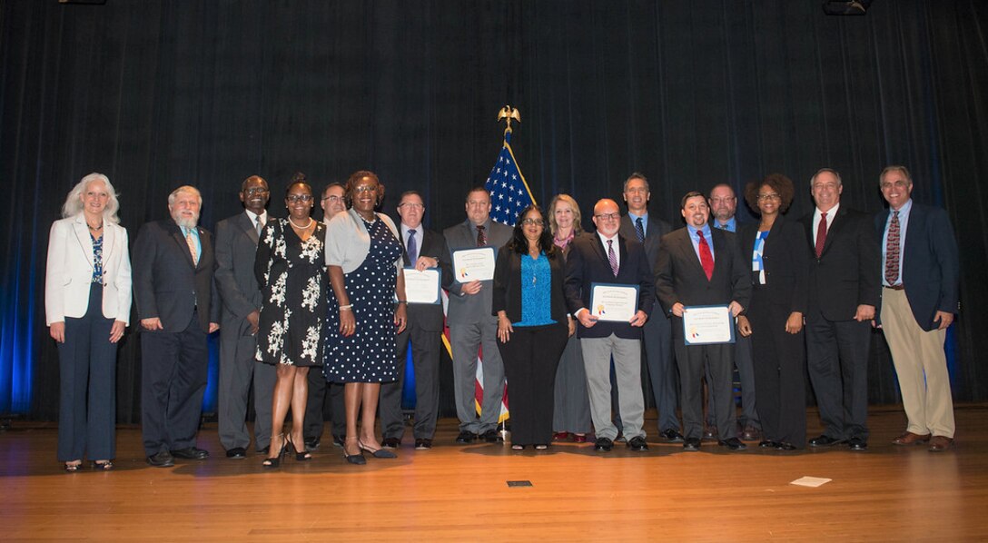 Acting Deputy Assistant Secretary of Defense for Systems Engineering Kristen Baldwin, left, joins the DLA Value Engineering Achievement Award winners at the June 28 ceremony. Photo by Zane Ecklund.