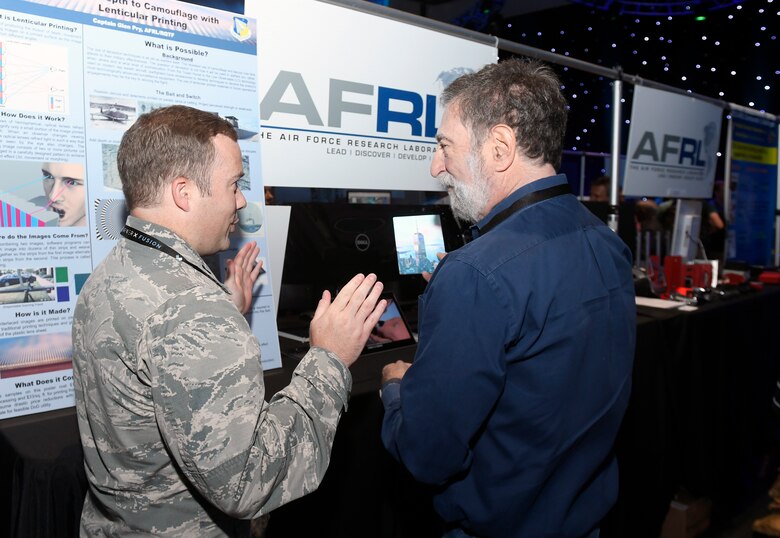 Capt. Glen Pry III, deputy chief, Fuels & Energy Branch, AFRL Aerospace Systems Directorate, explains how lenticular printed technology works and its potential effectiveness in a camouflage, concealment and decoy application to a Fusion Experience event attendee June 21, 2018. (AFWERX photo/Bobby Mack)