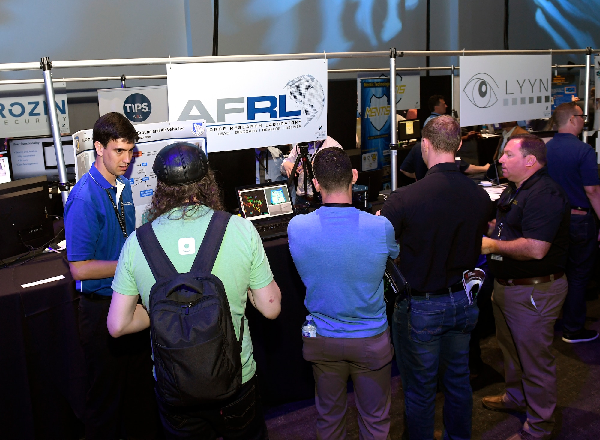Dr. Ryan Sherrill, a research aerospace engineer with the Air Force Research Laboratory Munitions Directorate, discusses autonomy algorithms with attendees at the AFWERX Fusion event. The Munitions Directorate has partnered with the Army Research Laboratory to research algorithms which allow multiple vehicles to autonomously and collaboratively explore and map an unknown space and send the map back to a human operator. (AFWERX photo/Bobby Mack)