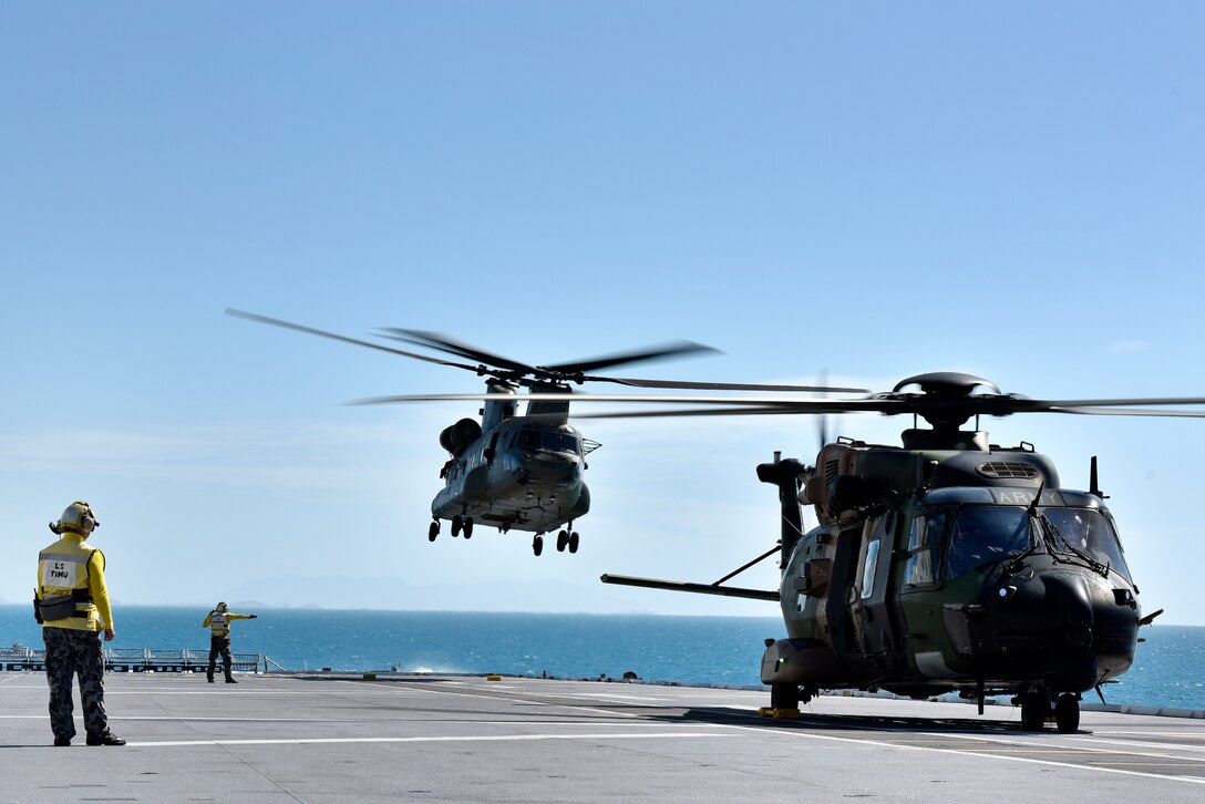 Australian Royal Navy Leading Seamans Timu and Harrison work on the flight deck with MRH90 and CH-53 helicopters during Exercise Sea Explorer aboard the HMAS Canberra at Sea June 9, 2018. The helicopters and soldiers were practicing rescue and recovery missions as part of the overall Ex Sea Series 18. The series is designed to train Australian Forces and get them amphibious ready. U.S. Marines and Sailors with Marine Rotational Force - Darwin 18 are working alongside the Australian Defence Force as part of the Amphibious Task Group.