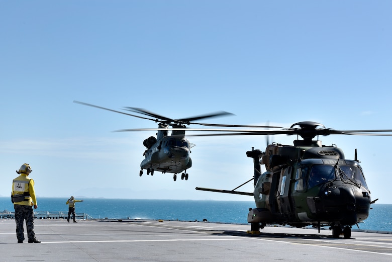 Australian Royal Navy Leading Seamans Timu and Harrison work on the flight deck with MRH90 and CH-53 helicopters during Exercise Sea Explorer aboard the HMAS Canberra at Sea June 9, 2018. The helicopters and soldiers were practicing rescue and recovery missions as part of the overall Ex Sea Series 18. The series is designed to train Australian Forces and get them amphibious ready. U.S. Marines and Sailors with Marine Rotational Force - Darwin 18 are working alongside the Australian Defence Force as part of the Amphibious Task Group.