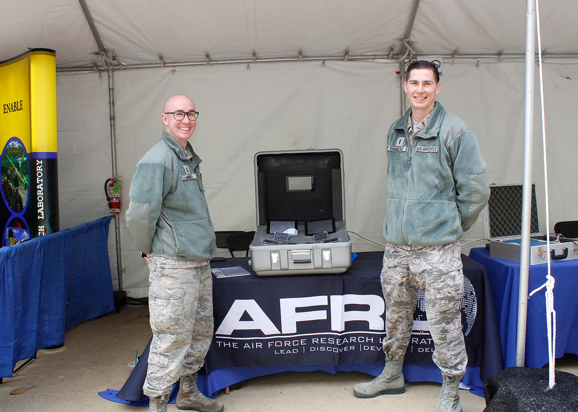 Air Force Research Laboratory scientist 1st Lt Simeon Hanks on the left and 2nd Lt. Parker Van Sickle at a directed energy technology exhibit shown in front of their high power microwave display.