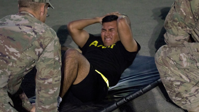 U.S. Army Spc. Julio Tepehua-Tello, a culinary specialist assigned to the 665th Engineer Utilities Detachment, U.S. Army Central, grimaces as he pulls himself up during the sit-up event of the Army Physical Fitness Test at U.S. Army Central's Best Warrior Competition at Camp Arifjan, Kuwait, June 28, 2018. The Best Warrior Competition promotes combat readiness among Soldiers by focusing on the importance of physical fitness in the U.S. Army.