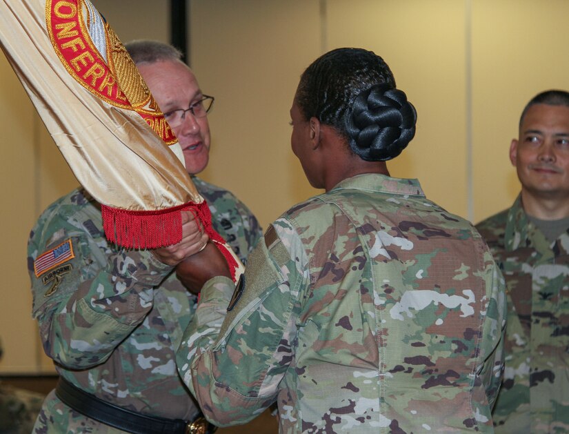 Col. Kim M. Thomas, outgoing commander of the 408th Contracting Support Brigade, passes the unit colors to Brig. Gen. Paul H. Pardew, commanding general, U.S. Army Contracting Command, during a change-of-command ceremony at the Carolina Skies Club and Conference Center at Shaw Air Force Base, South Carolina, June 22, 2018.