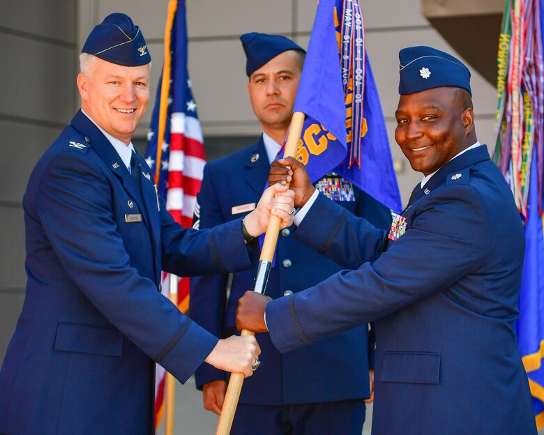 Col. W. Scott Angerman, commander of the 50th Network Operations Group, passes the 50th Space Communications Squadron guidon to Lt. Col. Anthony Lang, incoming commander of the 50th SCS, during a change of command ceremony at Schriever Air Force Base, Colorado, June 21, 2018. Lang previously served as the chief of Cyberspace Plans and Strategy Branch, North American Aerospace Defense Command and U.S. Northern Command at Peterson Air Force Base, Colorado. (U.S. Air Force photo by Kathryn Calvert)