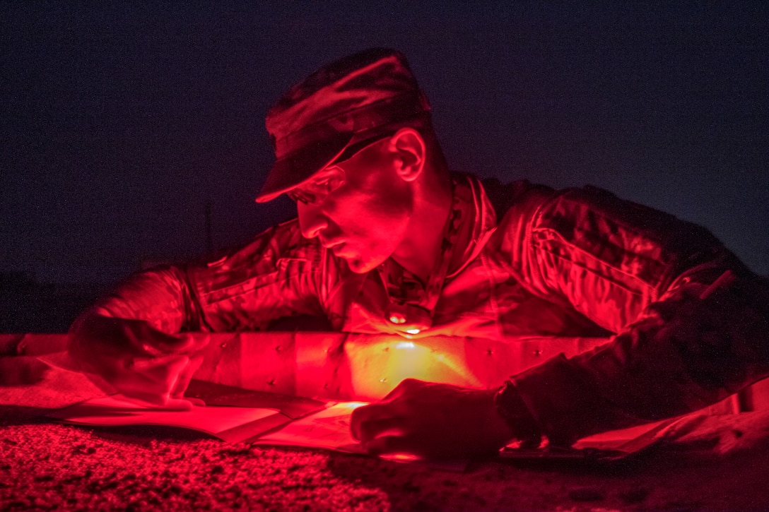A soldier using a red light marks on paper.