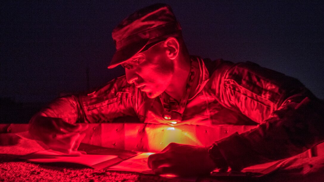 A soldier using a red light marks on paper.