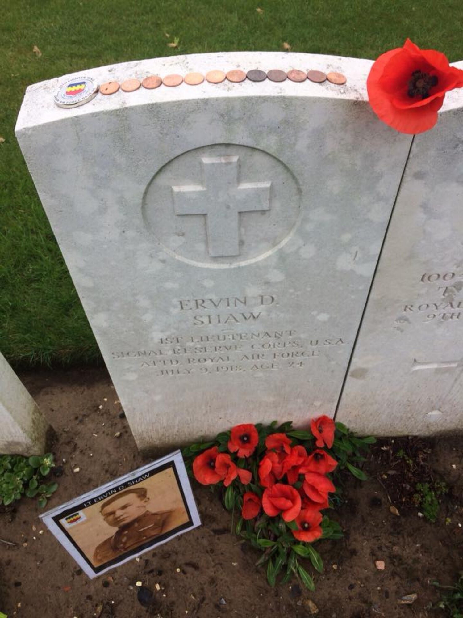 A photo of Royal Canadian Air Force 1st Lt. Ervin David Shaw, 48th Squadron Bristol F2B Brisfit pilot, is placed next to his grave at Regina Trench Cemetery, Courcelette, Somme, France, circa May 2018.