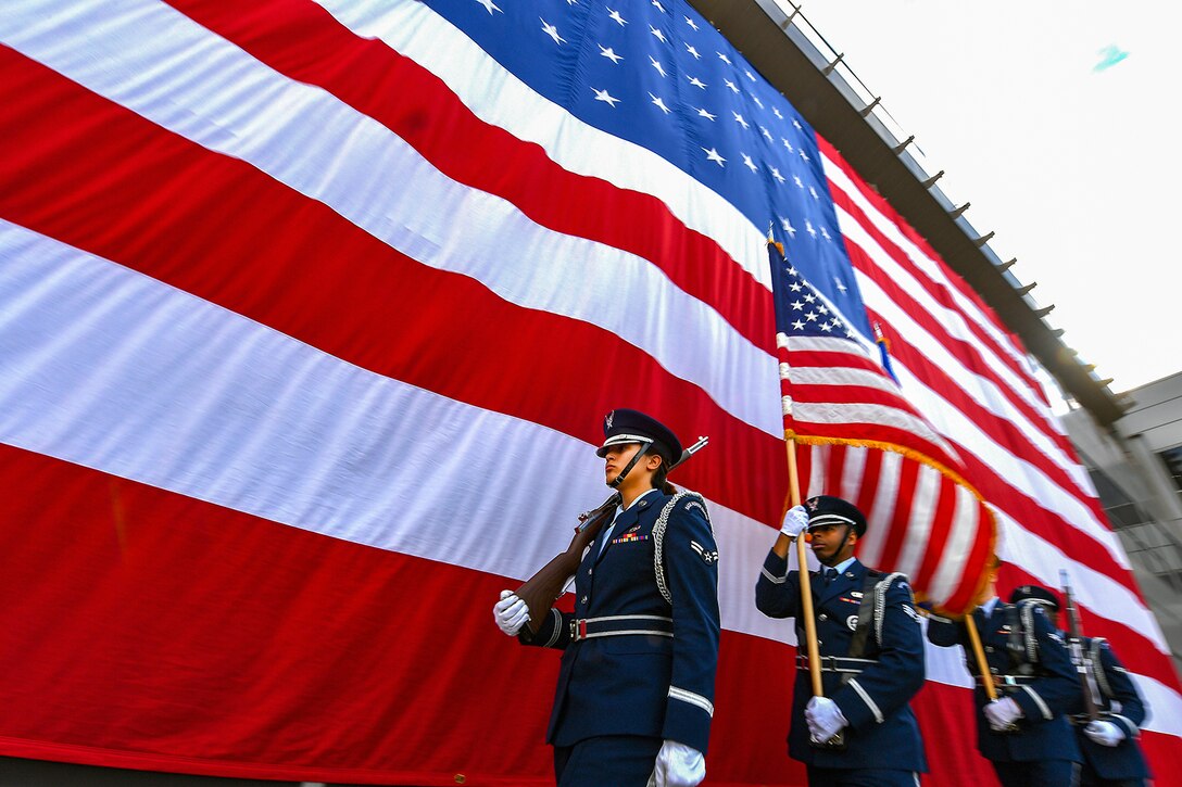 Airmen line up next to an American Flag