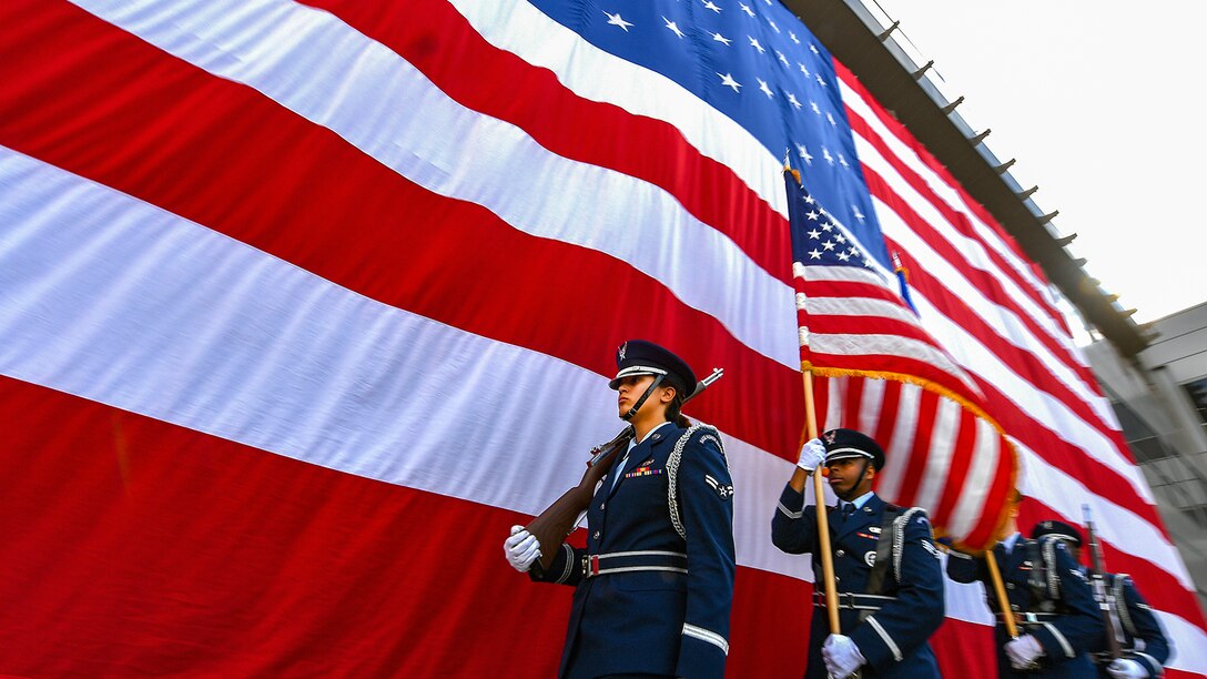 Airmen line up next to an American Flag