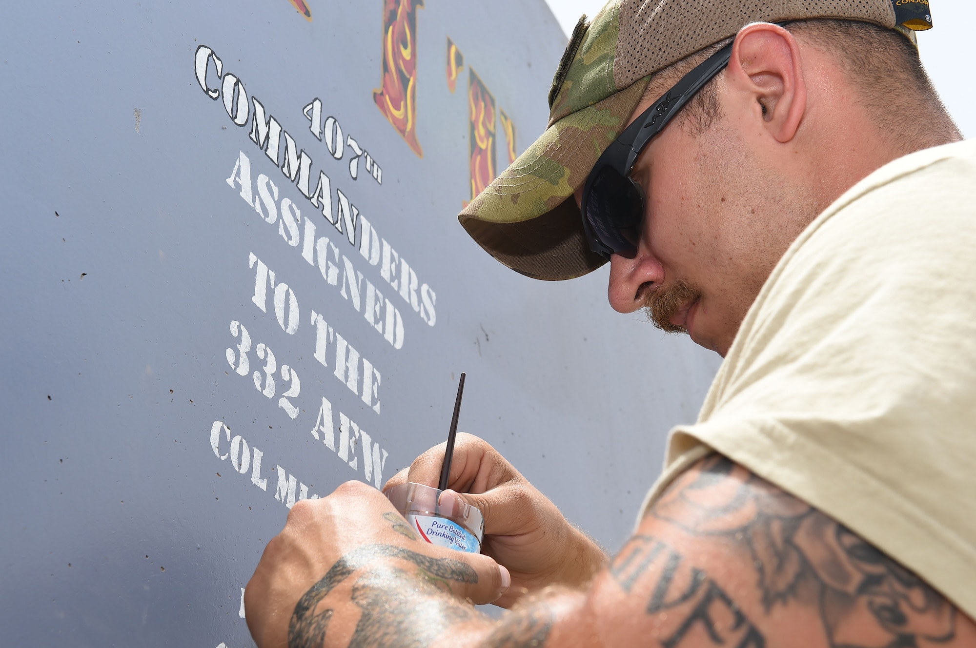 Airman dips paint brush into paint