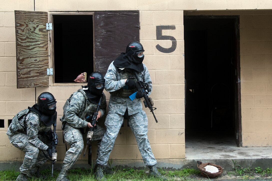 Airmen from the 23d Security Forces Squadron (SFS) prepare to clear a building during a Force on Force training scenario, June 29, 2018, at Moody Air Force Base, Ga. This training was held to ensure SFS Airmen are proficient in various tactics and procedures such as: building clear out, team movements, hostage rescue and properly applying cover fire. The scenario required Airmen to maneuver through multiple buildings to rescue a simulated victim guarded by opposing forces. (U.S. Air Force photo Airman 1st Class Eugene Oliver)
