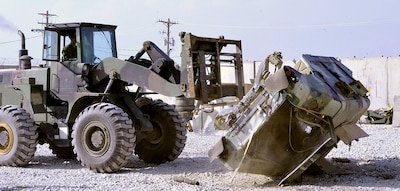 A forklift driven by Army Pfc. Cody Taylor, wheeled vehicle mechanic, Materiel Readiness Branch, 1st Cavalry Division Resolute Support Sustainment Brigade, flips a vehicle as part of the Afghan National Defense Security Forces 1050 DEMIL Program at Bagram Airfield, Afghanistan.
