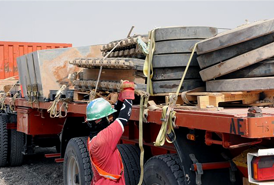 A foreign national augmentee at a mobile redistribution yard tightens the straps on a load of scrap metal at Joint Base Balad, Iraq. The scrap metal is to be delivered to DLA Disposition Services so that it can be disposed of properly.