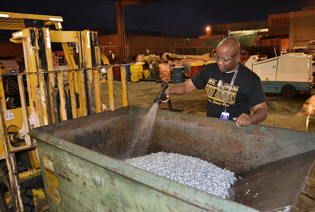 Charles Miller, a Fleet Readiness Center Southeast material identifier, washes a bin of aluminum scraps. Washing the scraps removes oil residue and dust so the metal can be taken to DLA Disposition Services for resale.