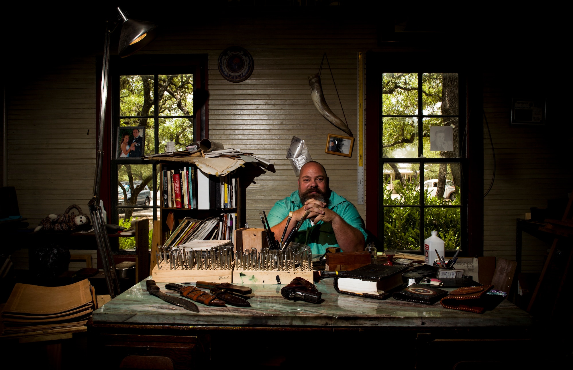 Former Army Sgt. Tony Fantasia poses for photo surrounded by leatherworking materials at his shop in San Antonio, Texas, June 29th, 2018. Working with leather has aided Fantasia’s battle with PTSD that he developed after his deployments to Southwest Asia as a medic. He now runs an outreach program for veterans focusing on various artistic outlets. (U.S. Air Force photo by Senior Airman Keifer Bowes)