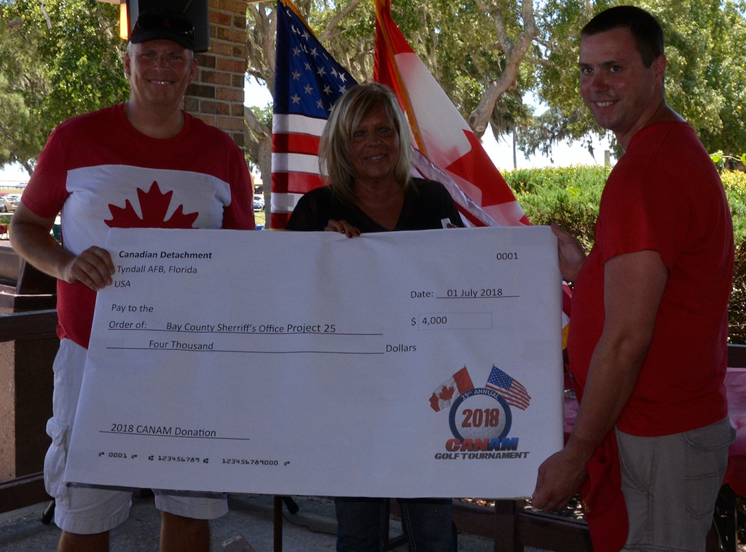 During the local celebration of Canada Day at Bonita Bay May 29, Royal Canadian Air Force LCol Brian Murray, Canadian Detachment Commander, Continental U.S. NORAD Region, and RCAF Capt Donald Ebsary, Communication and Information Directorate, 1st AF (AFNORTH)-CONR, present Becky Johns, Bay County Sheriff’s Office Project 25 Coordinator, a check for the Christmas toy-drive charity from funds raised during the Canadian-American Golf Tournament May 17. Each year, the Canadian Detachment chooses a local community charity to benefit from the annual golf event. Previous recipients have included Guardian Ad Litem and Panama City Marine Institute. (U.S. Air Force Photo by Mary McHale)