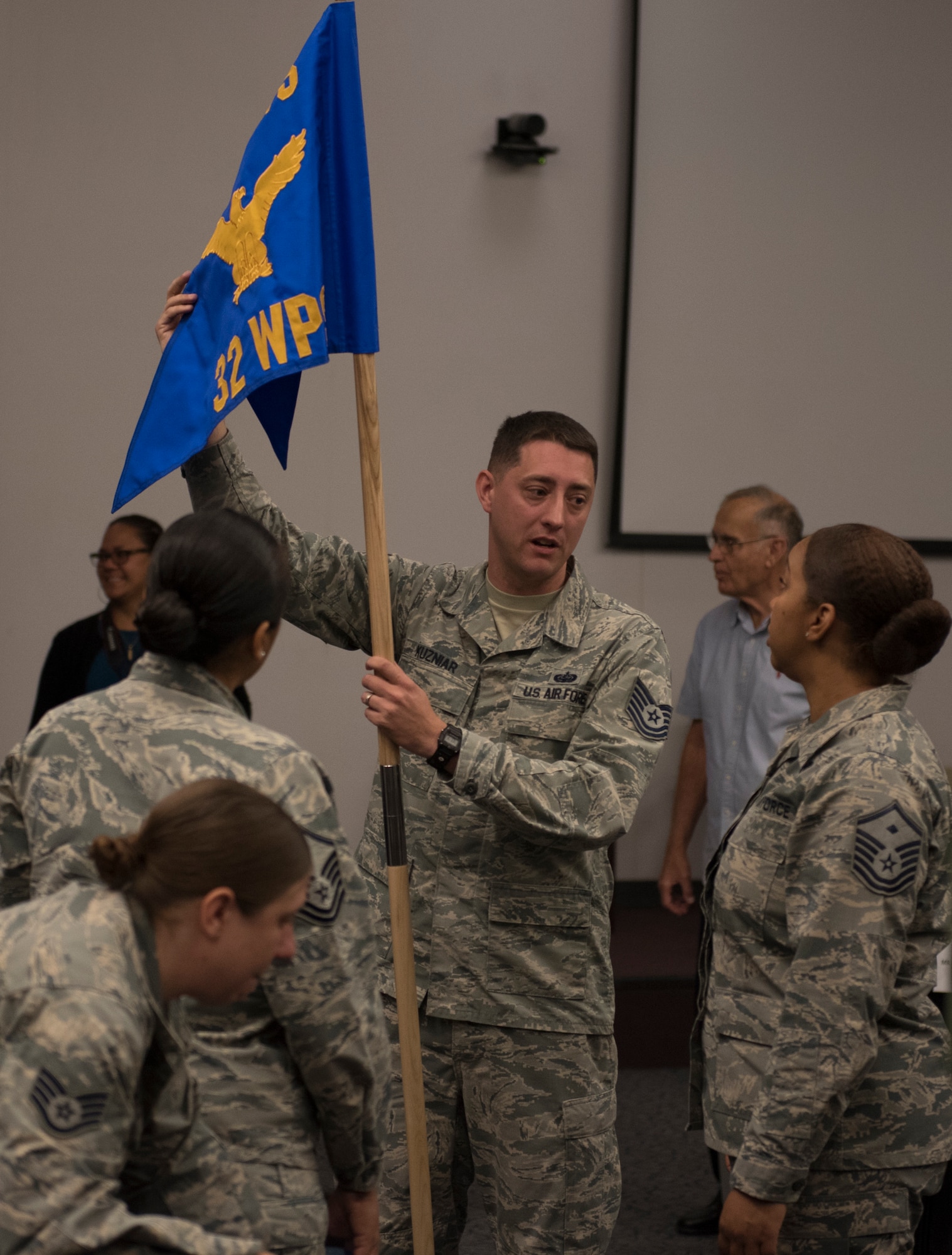 Tech. Sgt. Kieth Kuzniar, 32nd Weapons Squadron superintendent, shows off the new squadron guidon to Master Sgt. Brandi Love, U.S. Air Force Weapons School first sergeant, during an assumption of command ceremony at Nellis Air Force Base, Nevada, June 28, 2018. The 32nd WPS will focus on teaching Cyber Warfare Operations. (U.S. Air Force photo by Airman 1st Class Andrew D. Sarver)