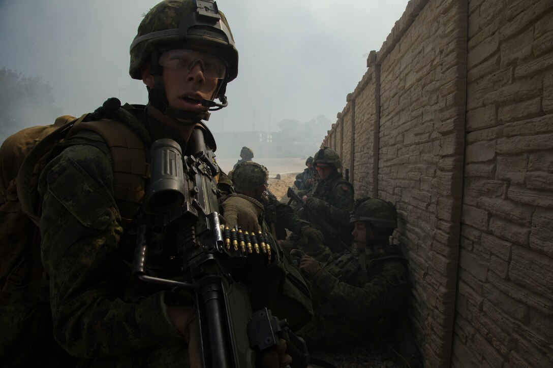 Canadian Army Pte. Felix Velamger, a line gunner with the Royal 22e Régiment prepares for a simulated raid with his squad at a combat town as part of Rim of the Pacific (RIMPAC) exercise at Marine Corps Base Camp Pendleton, California, July 3, 2018. RIMPAC demonstrates the value of amphibious forces and provides high-value training for task-organized, highly-capable Marine Air-Ground Task Forces enhancing the critical crisis response capability of U.S. Marines in the Pacific. Twenty-five nations, 46 ships, five submarines, about 200 aircraft and 25,000 personnel are participating in RIMPAC from June 27 to Aug. 2 in and around the Hawaiian Islands and Southern California.