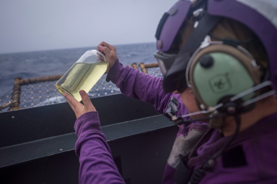 Gas Turbine System Technician (Mechanical) 3rd Class Mackenzie Mattox, from Middletown, Ohio, inspects a sample bottle of JP-5 fuel on the flight deck of the Ticonderoga-class guided-missile cruiser USS Chancellorsville (CG 62). Chancellorsville is forward-deployed to the U.S. 7th Fleet area of operations in support of security and stability in the Indo-Pacific region.